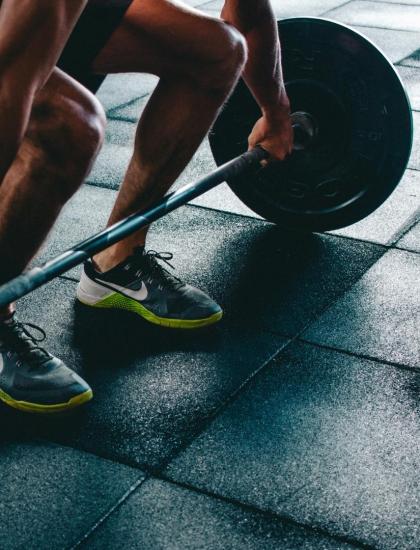 Persona solleva pesi in palestra su pavimento gommato.