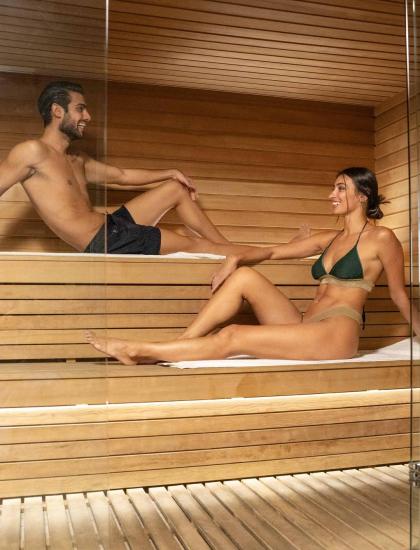 Due persone rilassano in sauna di legno.