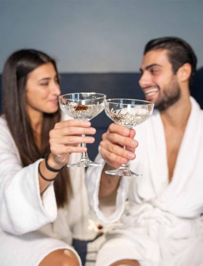 Couple toasting in bathrobes, crystal glasses.