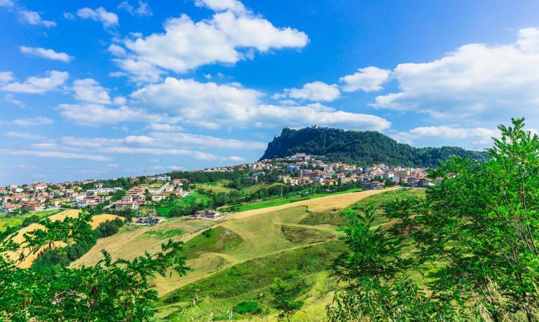 Hügelige Landschaft mit Stadt und blauem Himmel.