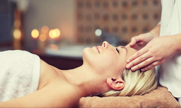 Relaxed woman receives head massage in a peaceful setting.