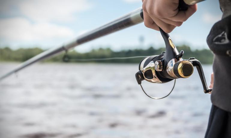 Persona che pesca con una canna da pesca vicino a un fiume.