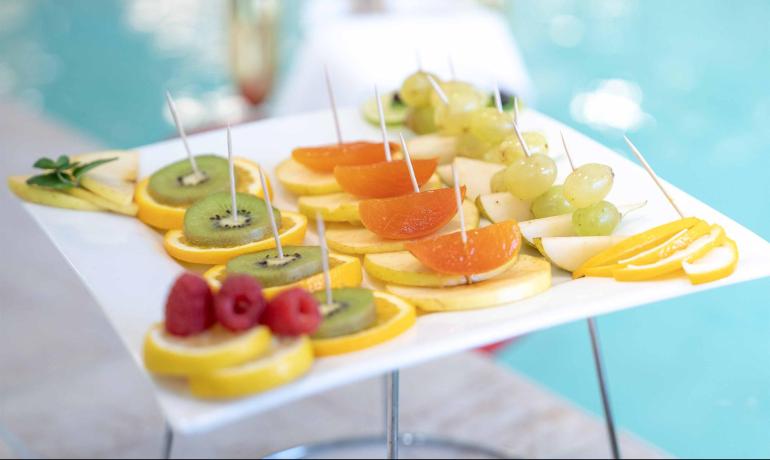 Piatto di frutta assortita vicino alla piscina, decorato con stuzzicadenti.