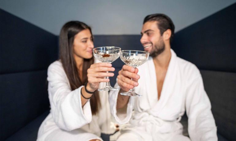 Couple toasting in bathrobes, crystal glasses.