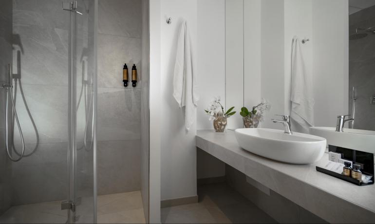 Modern bathroom with shower, sink, and mirror, decorated with flowers.