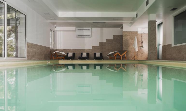 Indoor pool with loungers and shower, relaxing atmosphere.