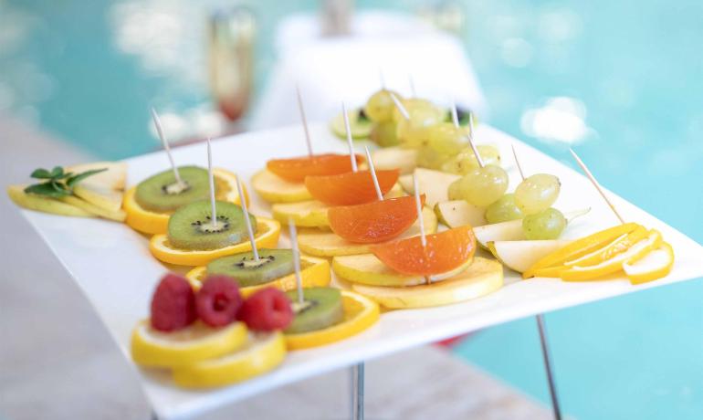 Fresh fruit on a white plate by the pool.